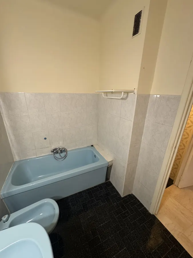 Baignoire bleue et carrelage noir avant rénovation
