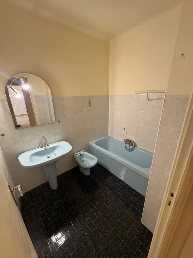 Salle de bain avant travaux : lavabo, bidet et baignoire bleus, carrelage ancien