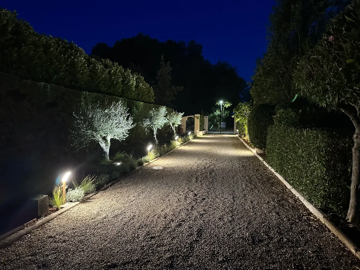 Allée en gravier bordée de bornes lumineuses, de nuit