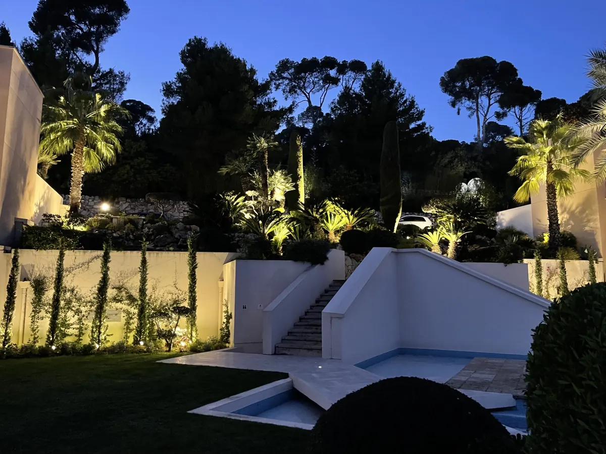 Piscine et jardin de villa éclairés à la tombée de la nuit