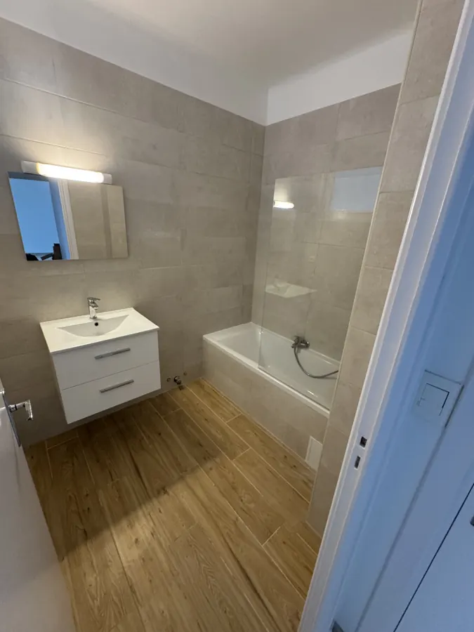 Salle de bain rénovée avec baignoire, meuble vasque et sol parquet