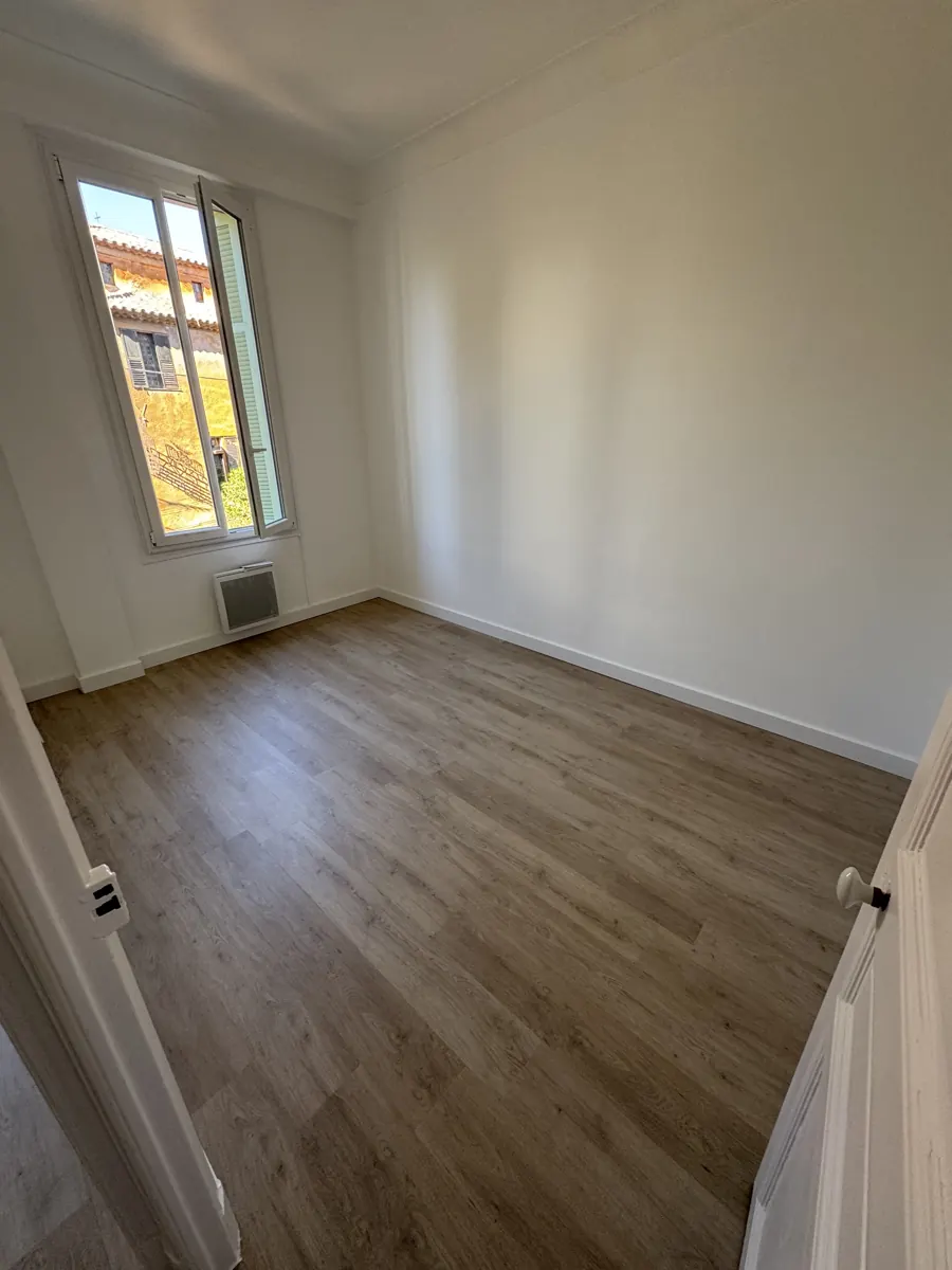 Chambre avec parquet et fenêtre donnant sur un jardin