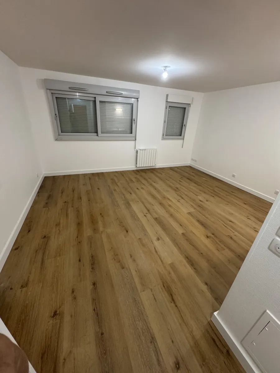 Chambre avec parquet, fenêtre à volets roulants et radiateur
